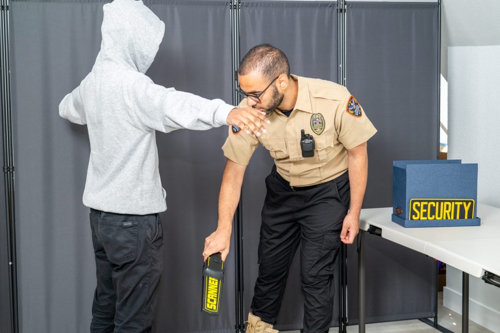 Equitab security officer conducting handheld metal-detector screening
